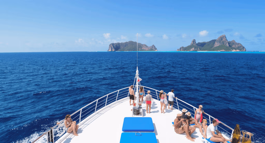 Tourists standing on the deck of a South Sea Cruises boat, heading toward South Sea Island across the calm blue waters of Fiji